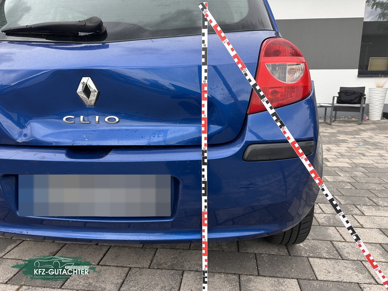 Schadensbeitrag Renault Clio: Delle in der Heckklappe, dokumentiert mit Maßstab